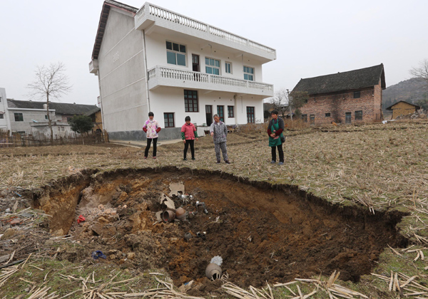 Villagers look at a sinkhole in a wheat field in Wenquan village, Hunan province on Jan 12, 2013. Sinking headache for farmers