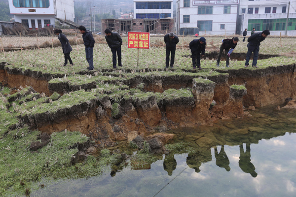 Villagers look at a sinkhole in a wheat field in Wenquan village, Hunan province on Jan 12, 2013. Sinking headache for farmers