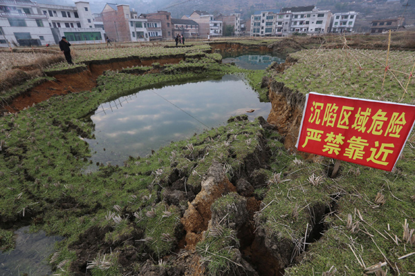Villagers look at a sinkhole in a wheat field in Wenquan village, Hunan province on Jan 12, 2013. Sinking headache for farmers