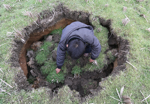 Villagers look at a sinkhole in a wheat field in Wenquan village, Hunan province on Jan 12, 2013. Sinking headache for farmers
