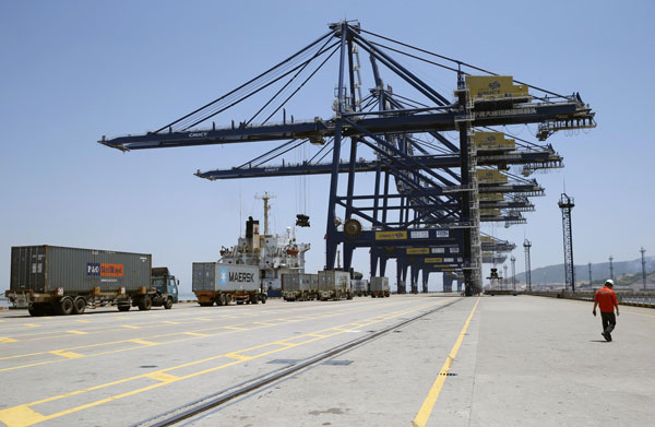 A worker walks past trucks as they line up to upload containers onto a ship at a port in Ningbo, Zhejiang province in this July 9, 2013 file photograph. China's economy caught in balancing act
