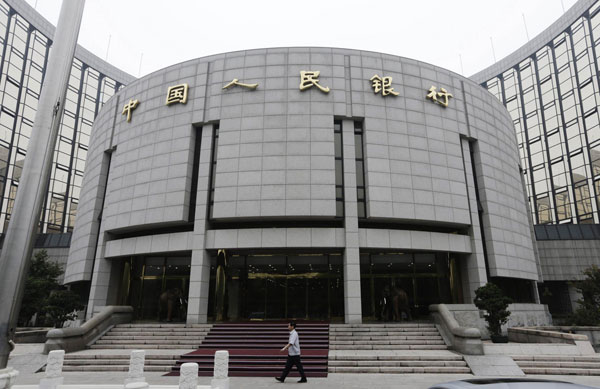 A staff member walks in front of the headquarters of the People's Bank of China (PBOC), the central bank, in Beijing, in this June 25, 2013 file photograph. China's economy caught in balancing act