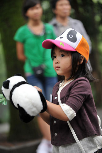 A 4-year-old girl holding a toy panda takes part in the birthday party for two giant pandas at Hangzhou Zoo, Aug 24, 2011. Pandas celebrate birthday at zoo in E China