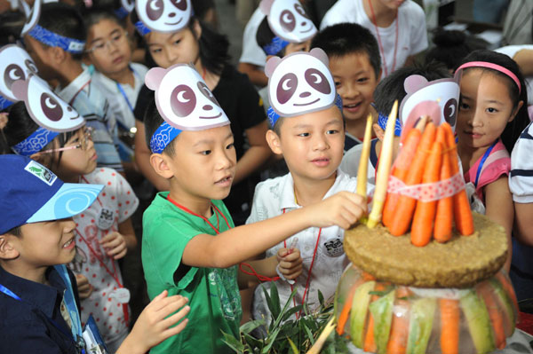 Children add bamboo shoots to the birthday cake for two giant pandas at Hangzhou Zoo, Aug 24, 2011. Pandas celebrate birthday at zoo in E China