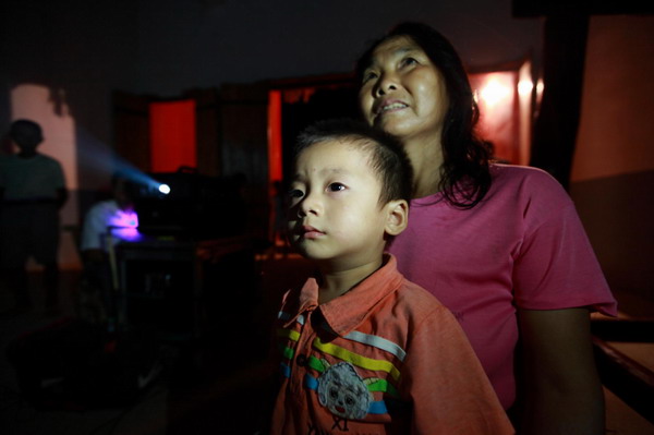 A boy watches a movie with his mother at an ancestral temple in Lijia village, Xinyu city, East China's Jiangxi province, Aug 31, 2011. The life of a rural projectionist