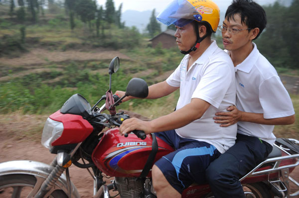 Two volunteers make their way to visit a poor family in Xinlu village, Chongqing municipality Sept 18, 2011. Motorbike volunteers bring help to kids in need