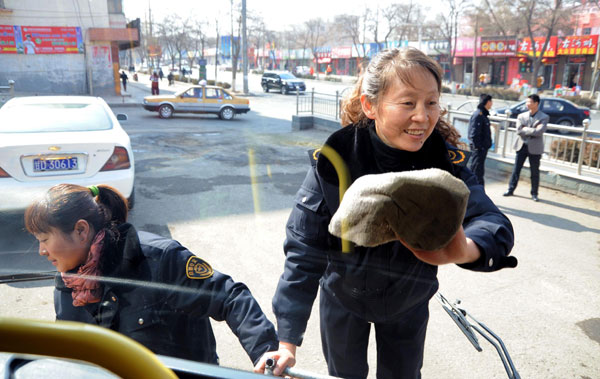 Deputy to the National People's Congress Zhang Huiping washes windows on a bus in Baiyin city, Gansu province on Feb 22. Deputy to be voice of bus drivers, passengers