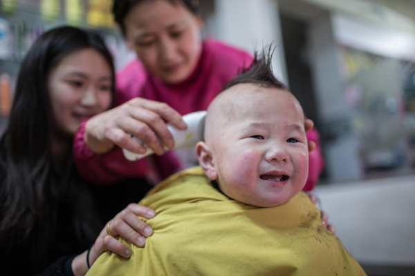 A child gets a haircut at a barbershop in Huaibei, Anhui province, March 13, 2013. Weekly Photos: March 11- 17