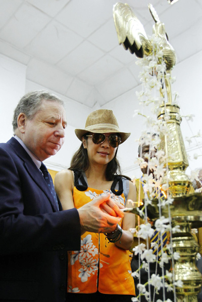 Jean Todt and Michelle Yeoh light an oil lamp at a vintage car rally