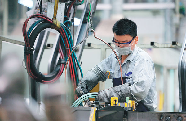 a worker performs a soldering job at an auto manufacturing ...