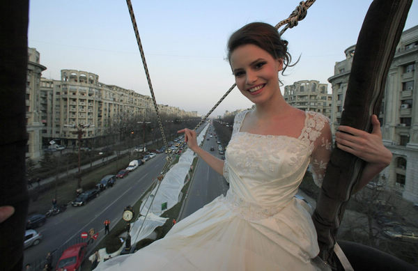 Emma, a 17 year-old model, sits on a hot air balloon as she wears the wedding dress with the longest tail in the world during a Guinness World Record attempt in Bucharest, March 20, 2012. Wedding dress with world's longest tail