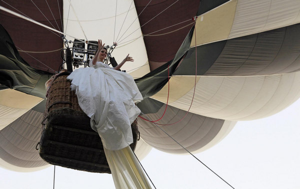 Emma, a 17 year-old model, waves from a hot air balloon as she wears the wedding dress with the longest train in the world during a Guinness World Record attempt in Bucharest, Romania, March 20, 2012. Wedding dress with world's longest tail