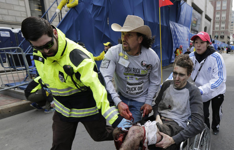 An injured man in a wheelchair is taken from the scene after explosions went off at the 117th Boston Marathon in Boston, Massachusetts, April 15, 2013. Attacks and threats affected sporting events in history