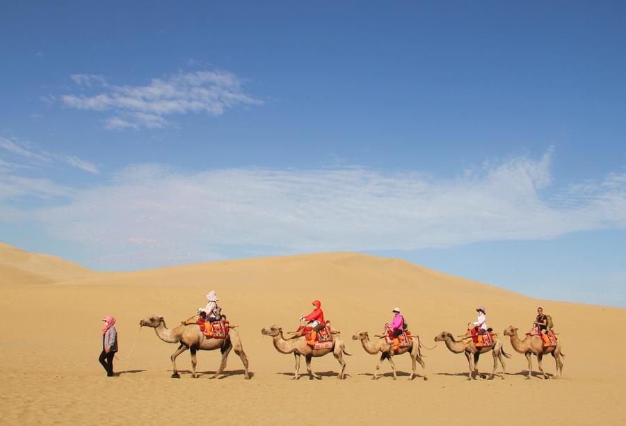 Tourists visit Mingsha Mountain in Dunhuang