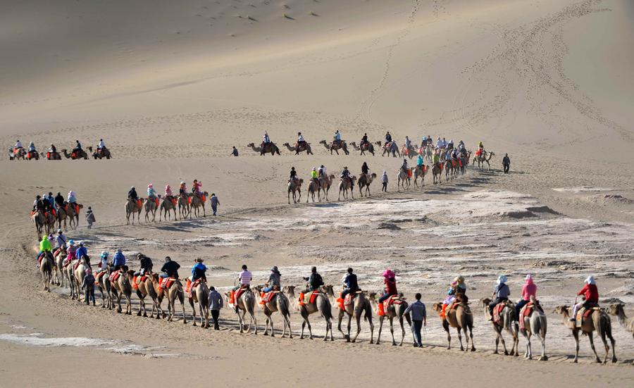 Tourists visit Mingsha Mountain in Dunhuang