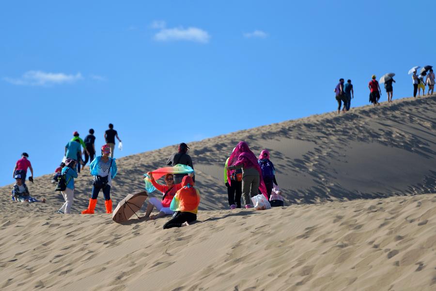 Tourists visit Mingsha Mountain in Dunhuang