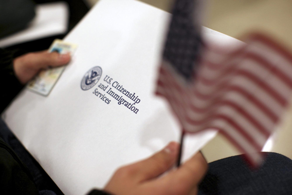 A man holds a US flag while receiving his proof of US citizenship during a ceremony in San Francisco, California, Jan 30, 2013. US immigration overhaul possible by 1st half of 2013