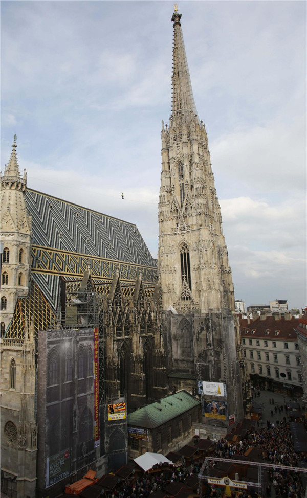 Austrian tightrope walker Christian Waldner passes the roof of St. Stephen's cathedral on a high line in Vienna, May 24, 2013. An act of balance