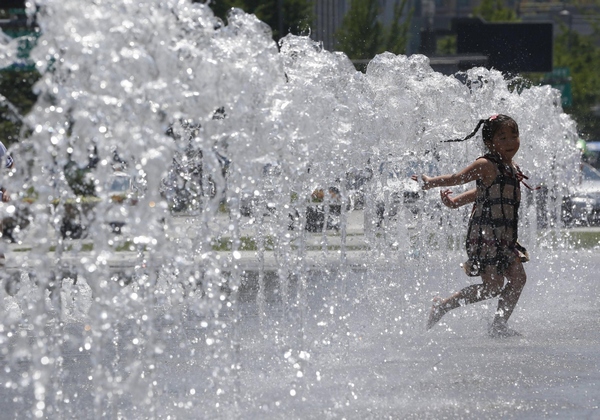 A girl plays at a fountain to cool down in the hot weather in central Seoul July 3, 2013. Girl plays at fountain to cool down in Seoul