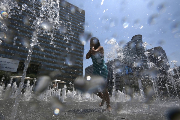 A girl plays at a fountain to cool down in the hot weather in central Seoul July 3, 2013. Girl plays at fountain to cool down in Seoul