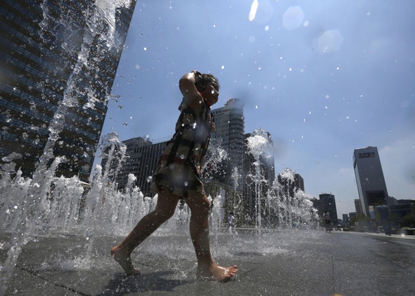 A girl plays at a fountain to cool down in the hot weather in central Seoul July 3, 2013. Girl plays at fountain to cool down in Seoul