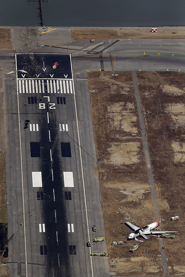 An aerial view shows rescue officials near an Asiana Airlines Boeing 777 plane after it crashed while landing at San Francisco International Airport in California on July 6, 2013. The plane, with 307 people on board, crashed and burst into flames as it landed at San Francisco International Airport on Saturday after a flight from Seoul, and initial reports said two people were killed and more than 130 sent to hospitals. After approaching the airport across San Francisco Bay, the plane appeared to strike the edge of the approach area of the runway. The tail came off and the aircraft left a trail of debris before coming to rest beside the runway. Asiana flight crashed at SFO