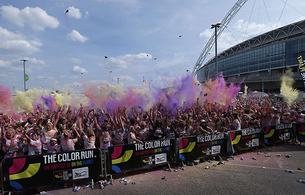Participants throw coloured paint into the air after finishing The Color Run outside Wembley Stadium in London, July 14, 2013. The Color Run is a five kilometre, un-timed race, held in cities across the US and also worldwide, with the aim of promoting healthy living, and the organizers choose a charity to benefit in each of the cities the run visits. Participants are doused from head to toe in different colours at each kilometre. Color Run in London promotes healthy living