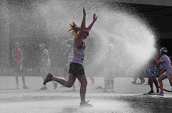 A runners is sprayed with cold water after finishing The Color Run outside Wembley Stadium in London, July 14, 2013. The Color Run is a five kilometre, un-timed race, held in cities across the US and also worldwide, with the aim of promoting healthy living, and the organizers choose a charity to benefit in each of the cities the run visits. Participants are doused from head to toe in different colours at each kilometre. Color Run in London promotes healthy living