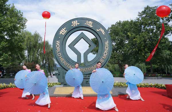 Dancers perform in front of sculpture of logo design for West Lake