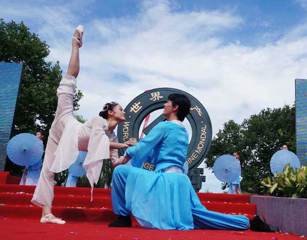Dancers perform in front of sculpture of logo design for West Lake