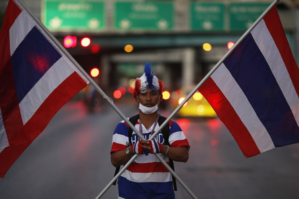 protester,in the colours of thailands national flag, holds two